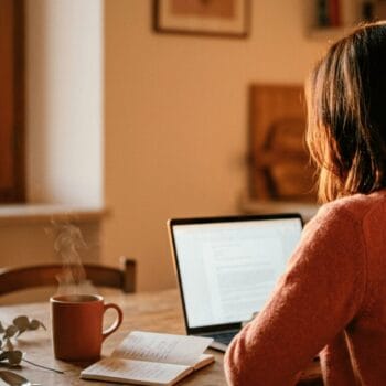 Donna al tavolo di cucina la sera che lavora al laptop, sistema di vendita online evergreen