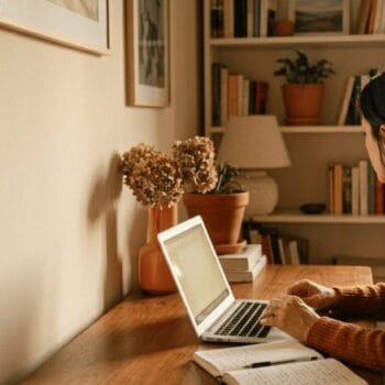 Donna al lavoro alla scrivania di casa che rivede i suoi appunti, simbolo di chi usa l’intelligenza artificiale ma resta l’autrice.