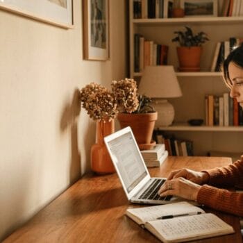 Donna che usa l'intelligenza artificiale per il business online, con laptop e appunti scritti a mano, mantenendo il controllo del lavoro