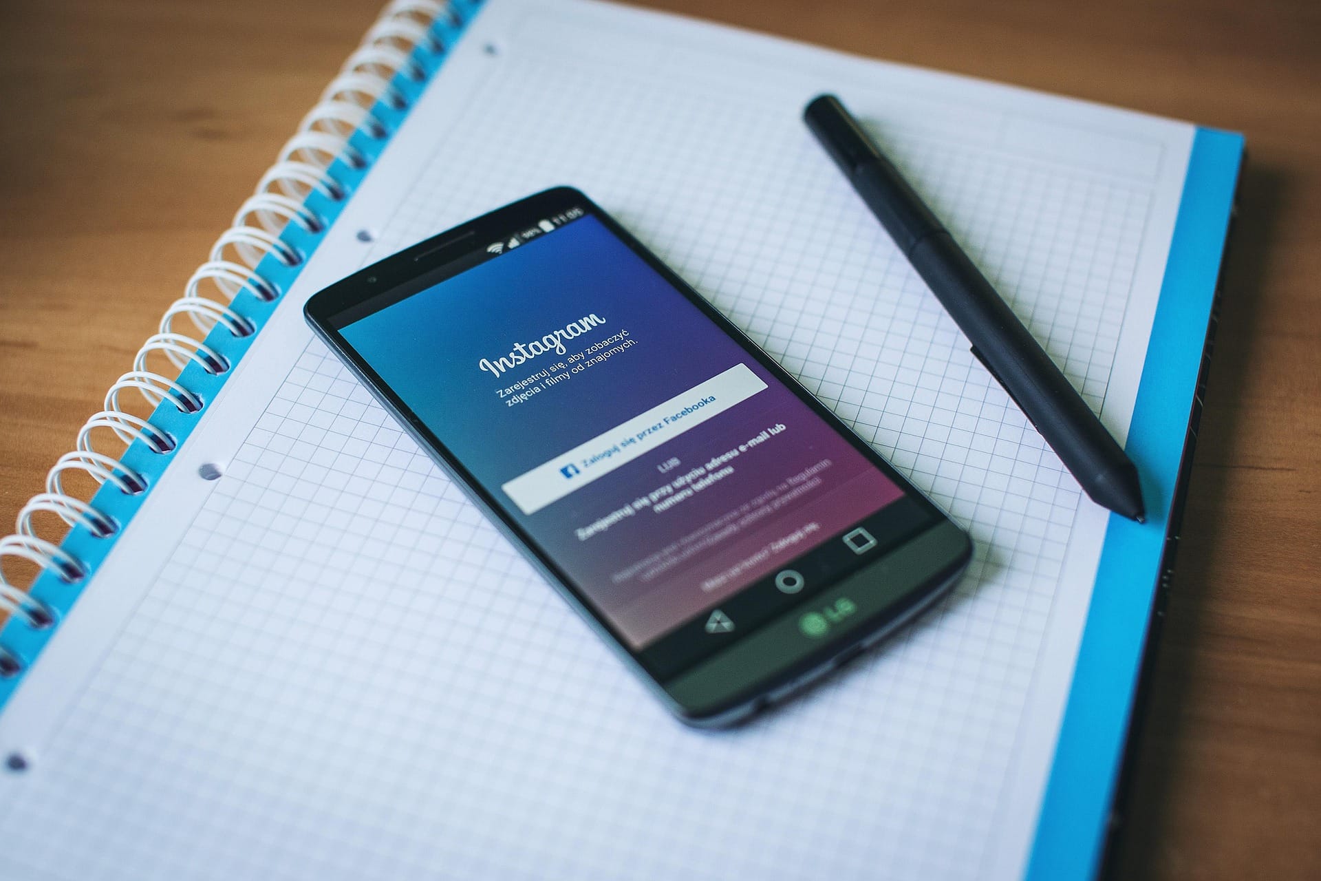 Un telefono con Instagram appoggiato su un quaderno a quadretti aperto, accanto a una penna