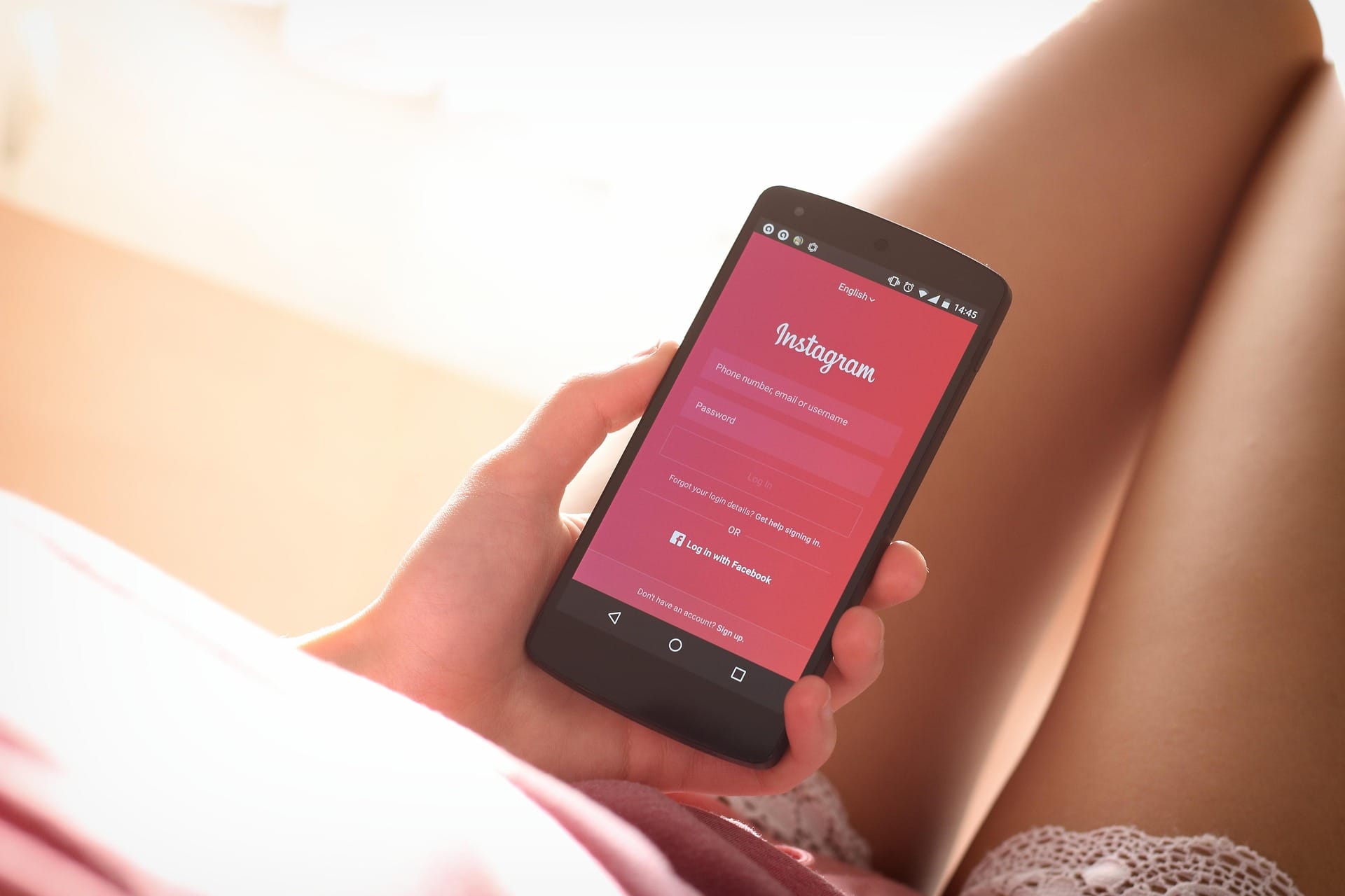 Una donna guarda lo schermo del telefono con Instagram aperto, seduta con la luce del pomeriggio