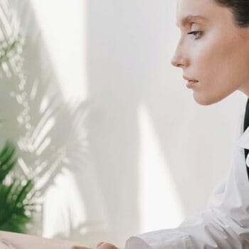 Donna di profilo al computer nella luce del pomeriggio, mentre lavora alla sua lista email