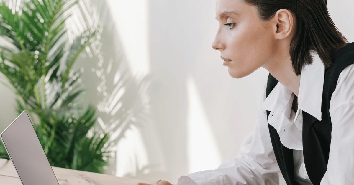Donna di profilo al computer nella luce del pomeriggio, mentre lavora alla sua lista email