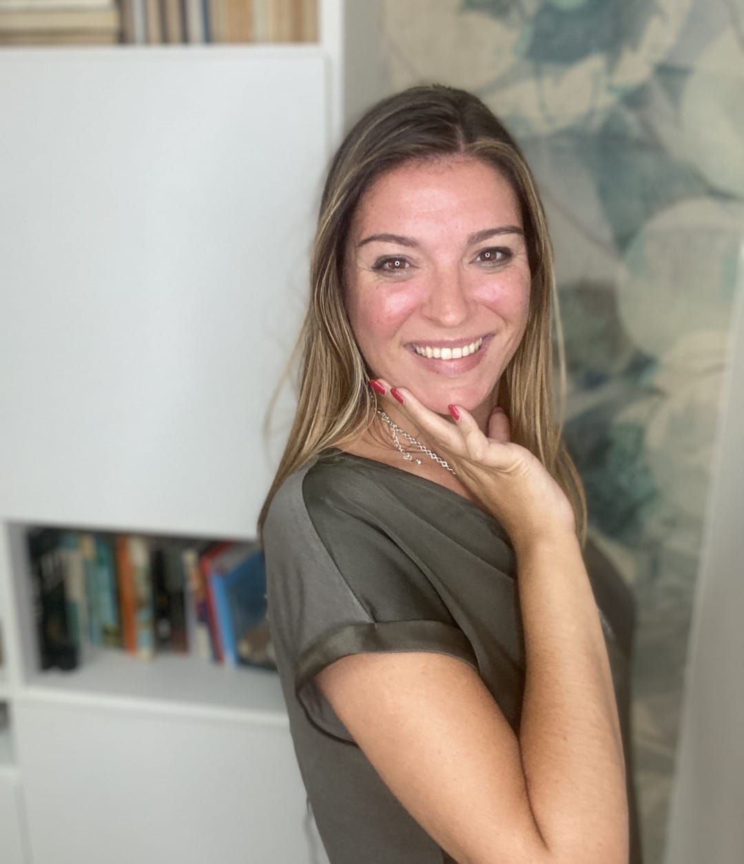 Martina Vitale, digital coach, sorride appoggiata a una libreria