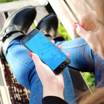 Donna seduta su una panchina che guarda il telefono, come chi trova una professionista su Instagram