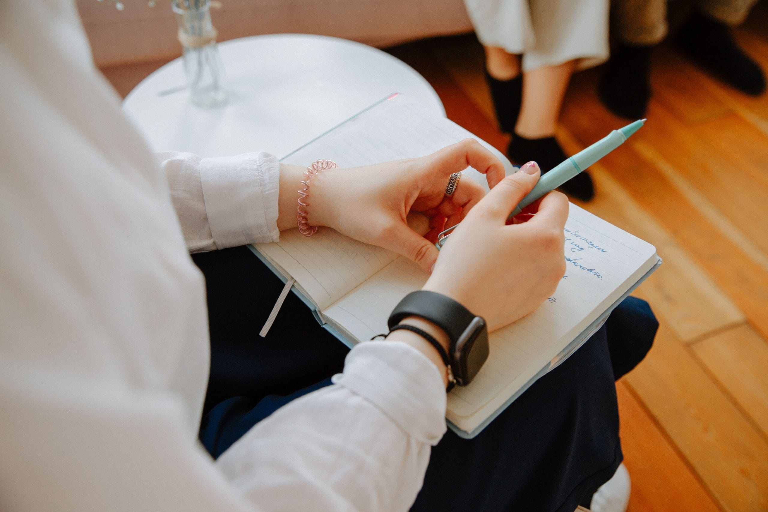 Mani di donna che scrivono con la penna su un quaderno a righe appoggiato sulle ginocchia