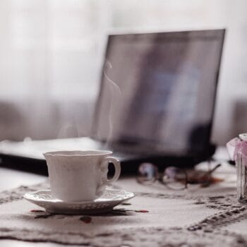Tazza di caffè e portatile su un tavolo di casa, la mattina in cui si decide di creare il sito da sola